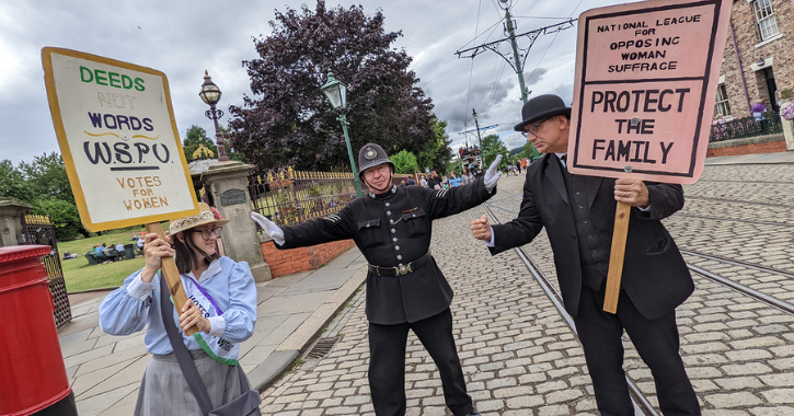 woman dressed as a suffragette holding placard alongside policeman and Edwardian man at Beamish Museum 